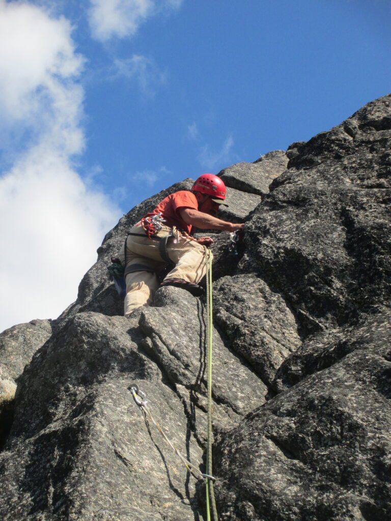 A climber in Leavenworth uses a fixed anchor in the rocks as a rope trails from his hip all the way down for his protection.