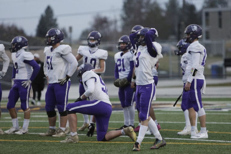 Nooksack Valley players react with some players holding the back of their helmets while others have their hands on their hips.