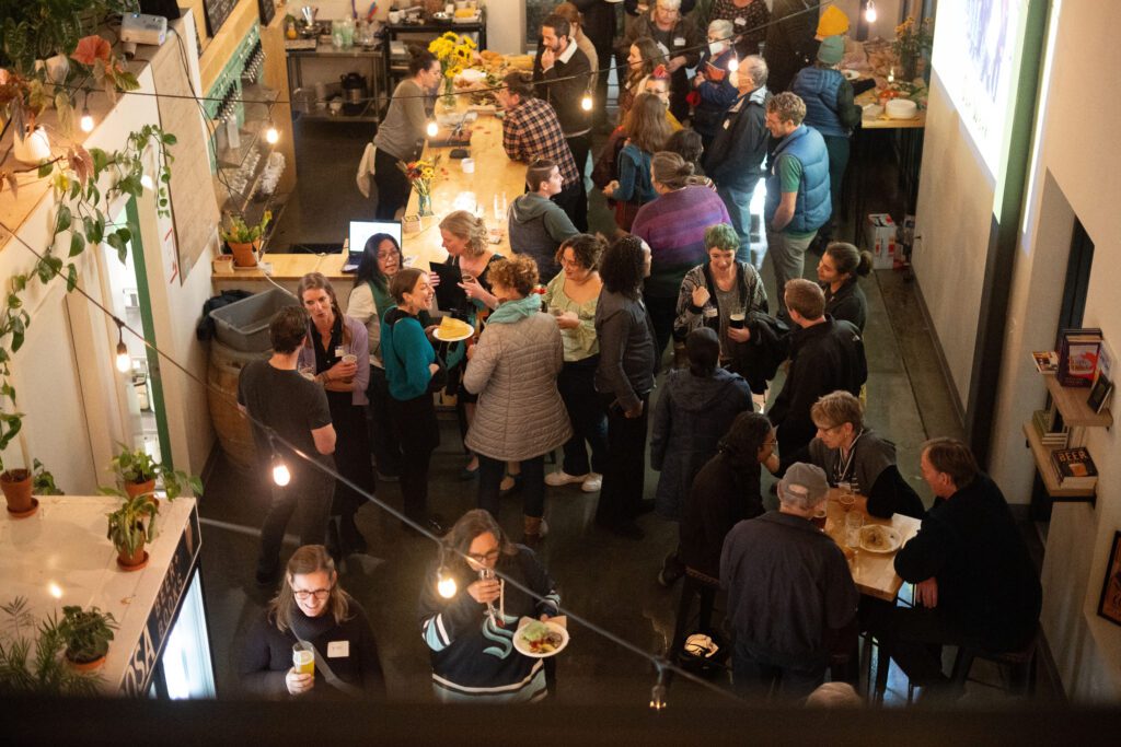 A crowd mingles at Ponderosa Beer and Books with many drinking and enjoying the food.