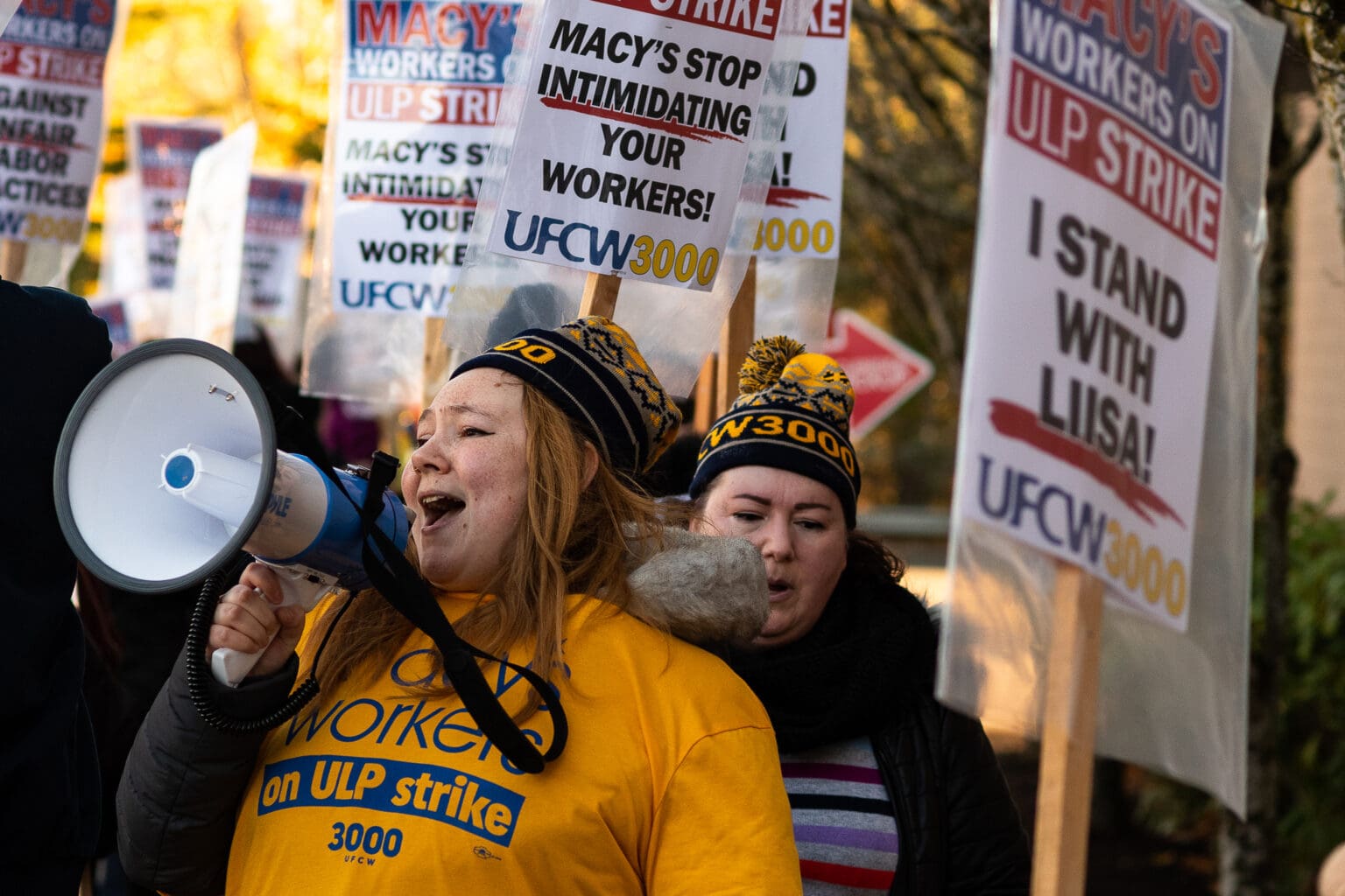 Samantha Wilson, a Macy's union employee, chants through a megaphone with many protestors chanting along behind her with signs supporting her strike.