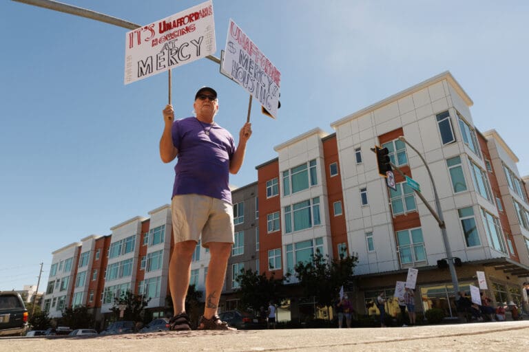 Along with a dozen others, Daniel Rinier, a resident of the Eleanor Apartments, protests on N. Forest Street about another rent increase for at the affordable housing complex.