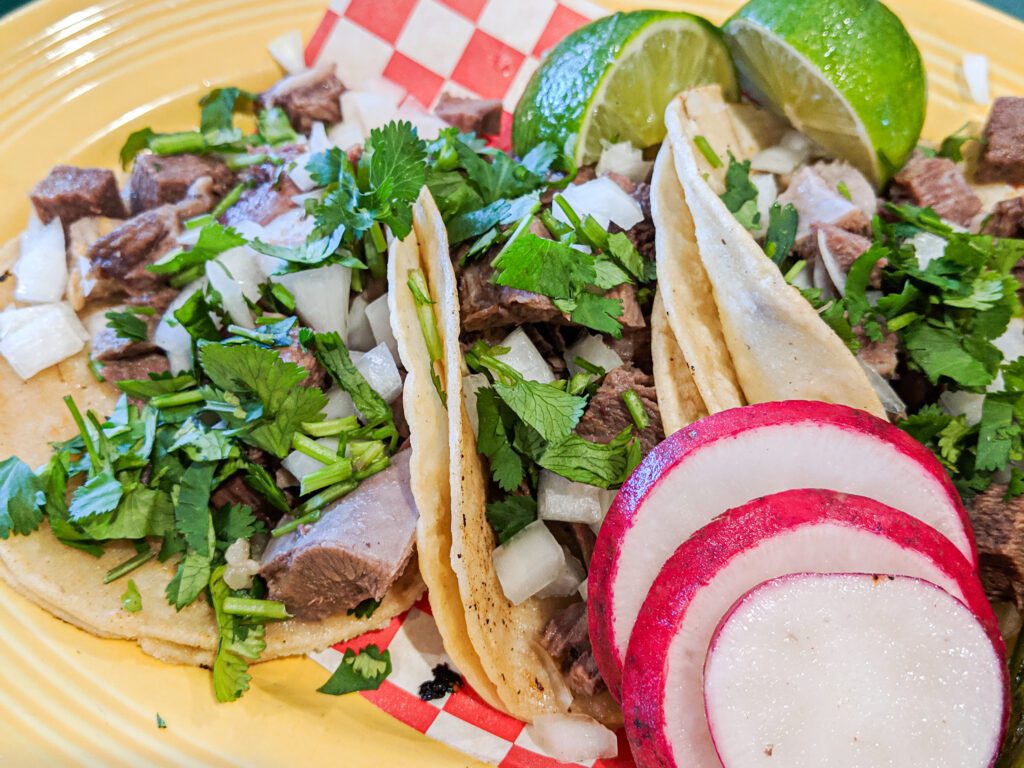Lengua acos served street-style served with slices of lime.
