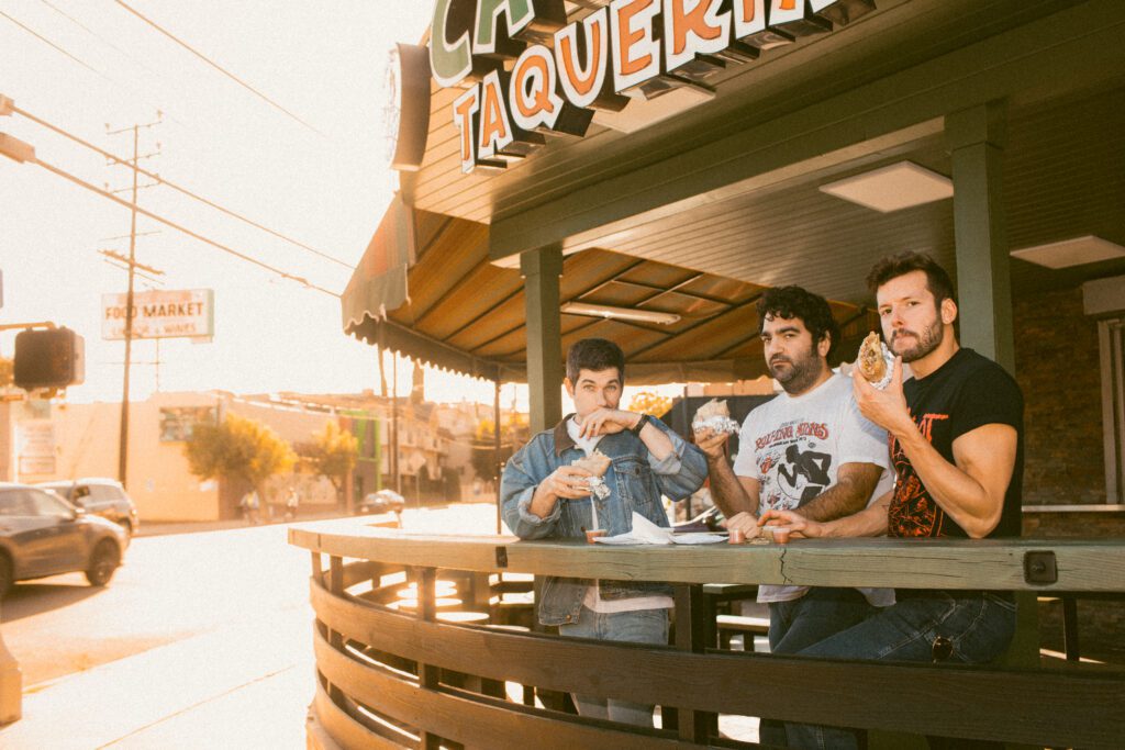 The Wolves of Glendale, a comedy rock trio enjoys burritos with dipping sauces in the outdoor seating of the restaurant.