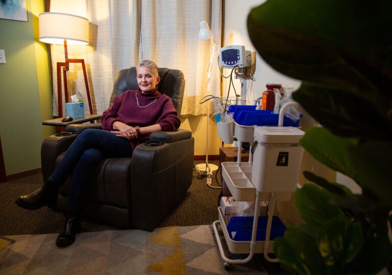 Dana LAST NAME sits in a recliner next to carts of medical equipment at King Health. The room is where patients undergo the ketamine treatment. Karen King said she designed the space to be warm, comforting and safe – different than a typial medical office.