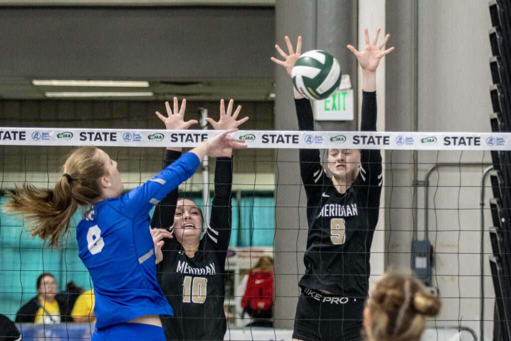 Meridian's Grace Wells (10) and Gracie Pap (9) with her eyes closed attempt to block a La Center spike.
