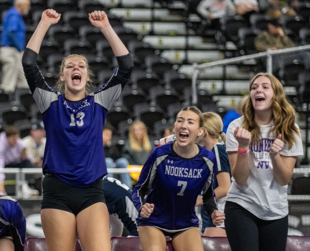 Grace DeHoog (13) and Annie Stremler (7) celebrate a point as they yell and raise their fists into the air.