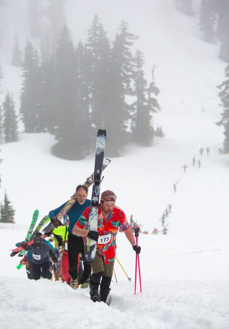 A line of skiers and snowboarder make the more than 800 ft elevation climb up the mountain to ski down.