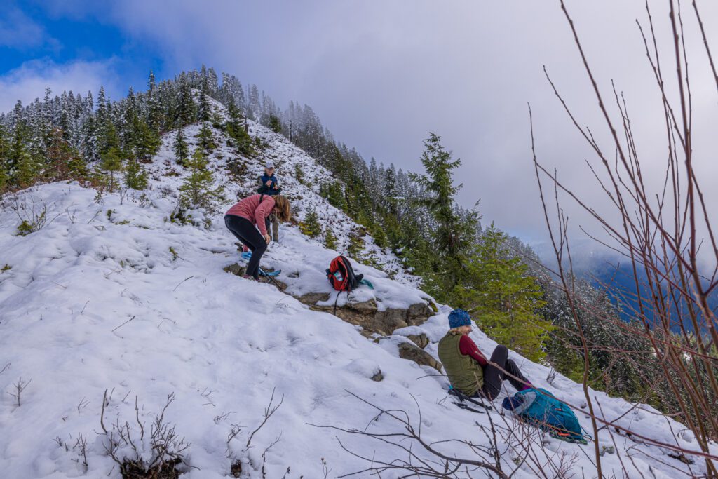 Hikers stop to slip into microspikes to continue their trek up the snowy mountain.