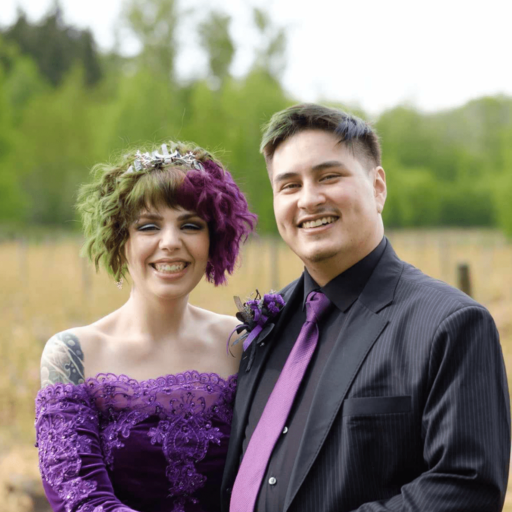Sam Chue, right, with his late wife Victoria Sprong smile at the camera while wearing matching purple outfits.