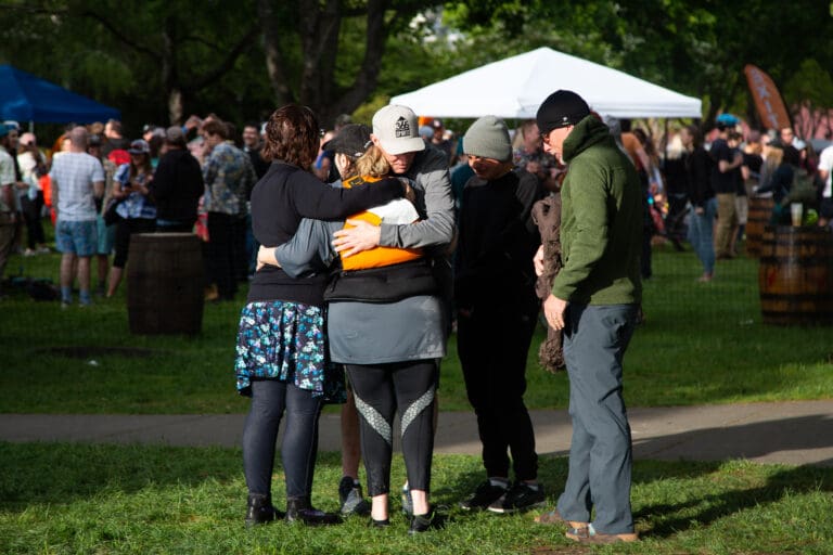Dawn Groves and friends hug, after learning the news of her teammate's death while on the Ski to Sea course at Maritime Park on May 29.