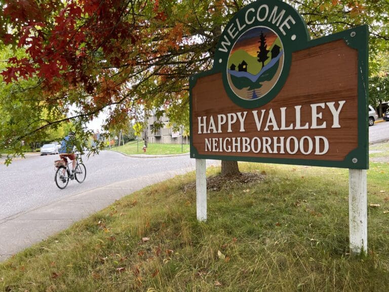 A biker passes by a Happy Valley neigbhboorhood sign.