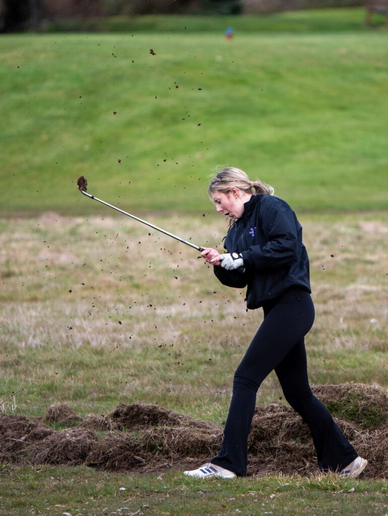 Nooksack Valley's Samantha Howe kicks up dirt after attempting to hit her ball out of a muddy ditch during the 2023 Whatcom County girls golf championships.