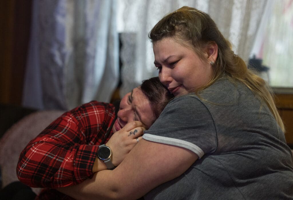 Alyshia Losey, left, is hugged by younger sister Elizabeth Babcock as the family of David Babcock talk about his death, in 2022, on Jan. 7. Babcock shot and killed by Sedro-Woolley police in February 2022. A 300-page report cleared the officer of wrongdoing.