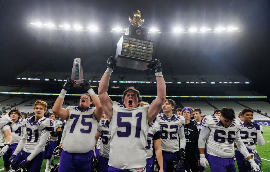 Anacortes players celebrate with the championship trophy after beating Tumwater 60-30 to take the 2A state championship title at Husky Stadium.