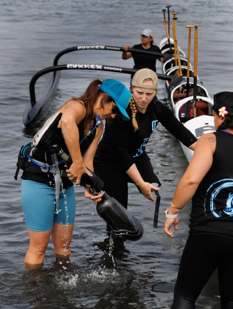 Suzanne McLelland pours out water from Tatiana Hoare’s prothetic leg before they get into their boat at The Bellingham Bay Classic outrigger canoe races held on Aug. 12 at Boulevard Park in Bellingham.
