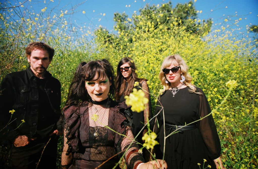 Los Angeles band Death Valley Girls posing for a photo in a dense meadow of yellow flowers.