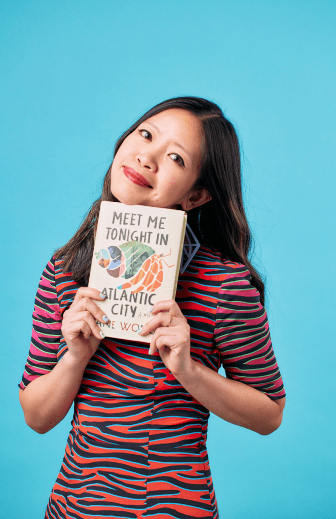 Author, Western Washington University professor and editor Jane Wong with her debut memoir "Meet Me Tonight In Atlantic City" in front of a bright blue backdrop.