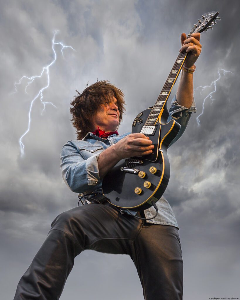 An edited photo of Randy Linder plays the guitar as thunder strikes behind him.