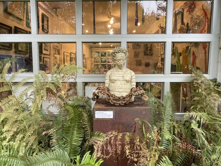 Matzke Fine Art Gallery and Sculpture Park on Camano Island has a clay bust at the store's window front surrounded by shrubbery.