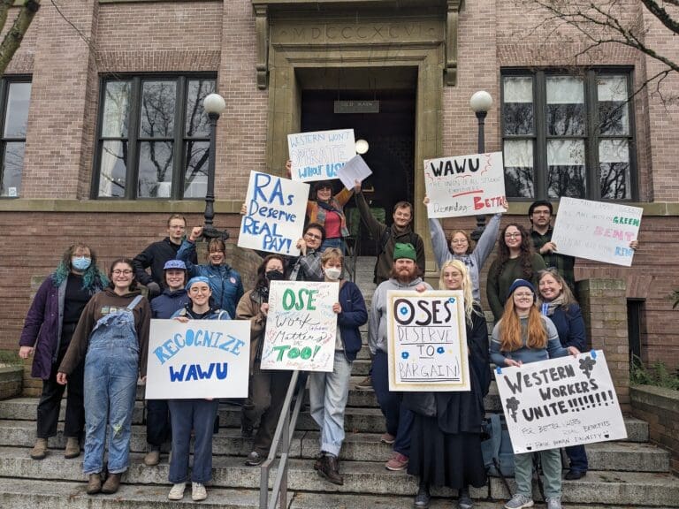 Operational student employees gathered on Western Washington University's campus steps hold up signs in celebration of filing for unionization.