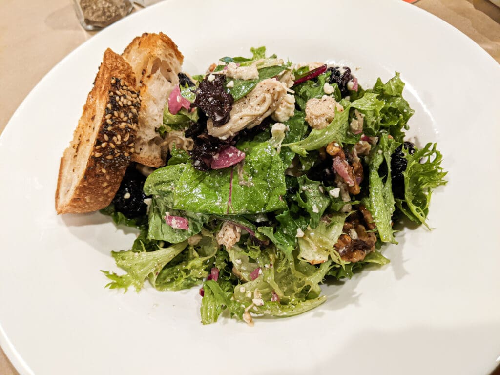 A chicken salad served with toasted bread on a white plate.