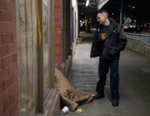 Emergency Medical Services Division Chief Scott Ryckman checks on a person huddled in a doorway on Commercial Street in Bellingham on Thursday, Feb. 15.
