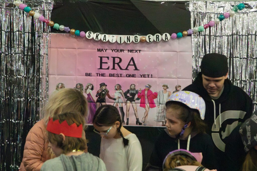 Event attendees were able to pose for photos in front of the "May Your Next Era Be the Best One Yet!" poster near the ice rink entrance.
