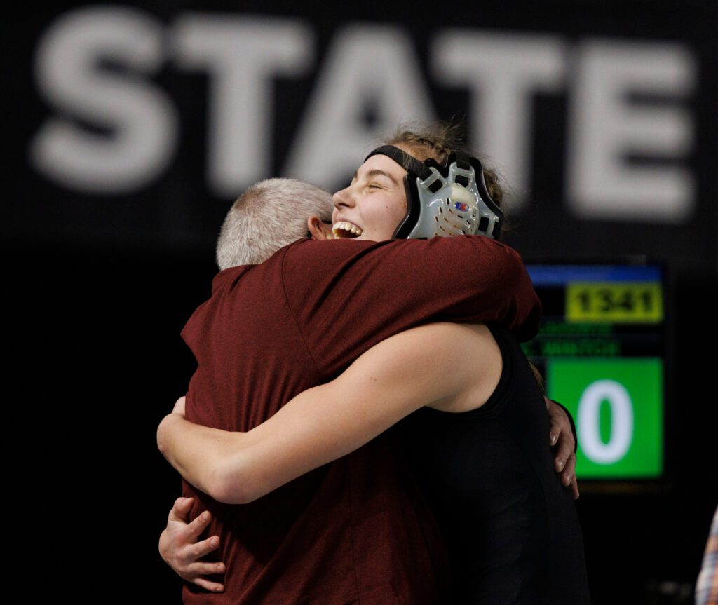 Mount Baker's Tyla Olson celebrates winning her match by hugging coach Clyde Blockley.