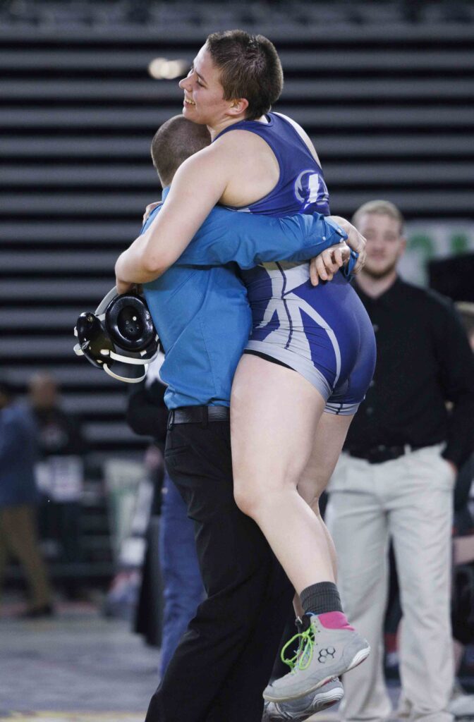 Bella Phillips is lifted into the air by their coach after winning the 190-pound state title.