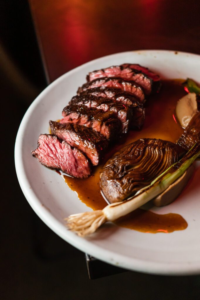 The roasted hangar steak at Carnal features sour grape glazed mushroom, charred scallion and veal jus.