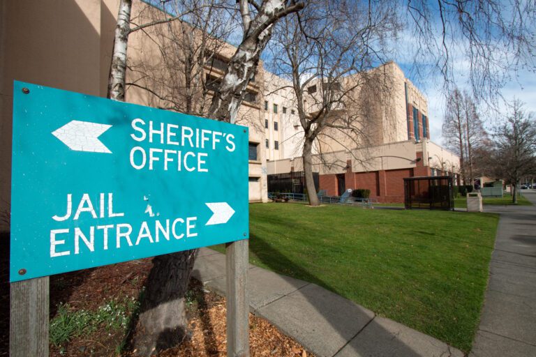 A blue jail sign is posted outside of the county jail.