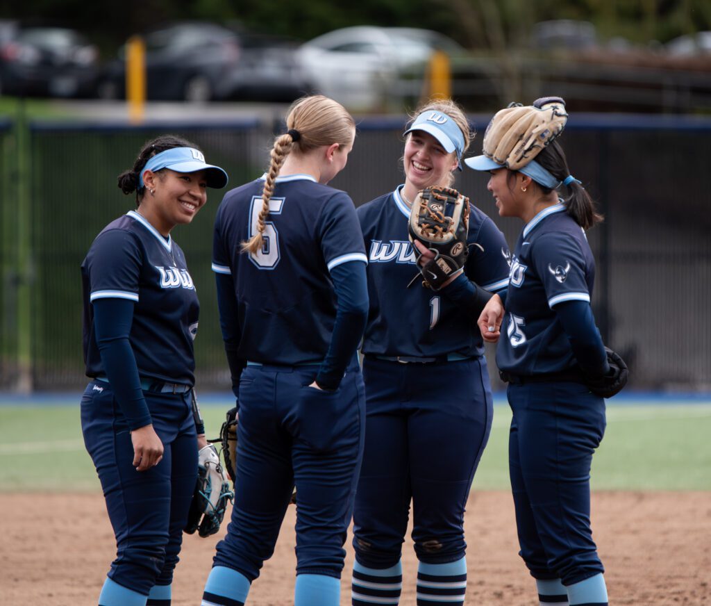 From left, Western infielders freshman Maleah Andrews, senior Ashley Jacobson, sophomore Hailey Rath and junior Kanilehua Pitoy smile during a mound visit March 2 during a home game against Saint Martin's at Viking Field.