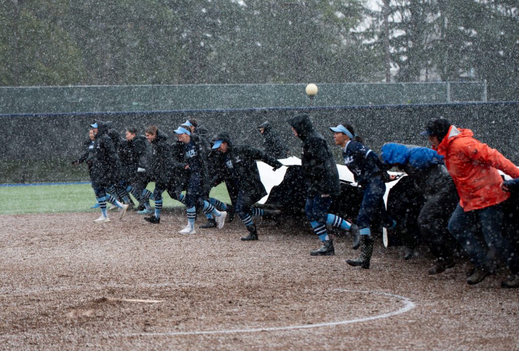 Western's softball team runs the tarp over the infield during a hail and snow delay Saturday, March 2 at Viking Field. The game continued and the Vikings took a 7-4 loss to Simon Fraser.