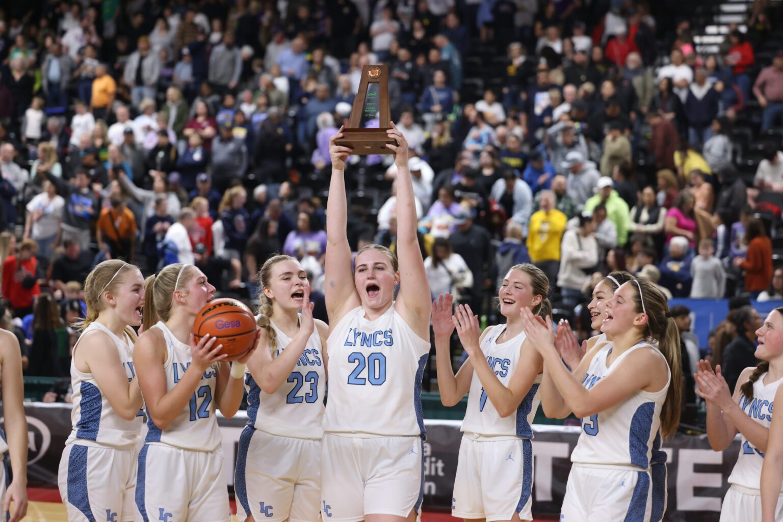 Lynden Christian’s Tabitha DeJong holds up the third-place trophy Saturday, March 2 after the Lyncs beat Wapato 72-64 in the 1A state tournament at the Yakima Valley SunDome.