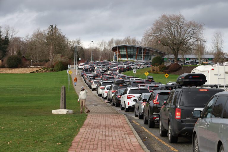 A pedestrian takes a picture next to heavy traffic leading all the way to Peace Arch border crossing.