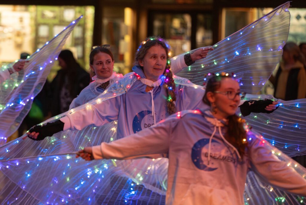 People spread their lighted winged capes.