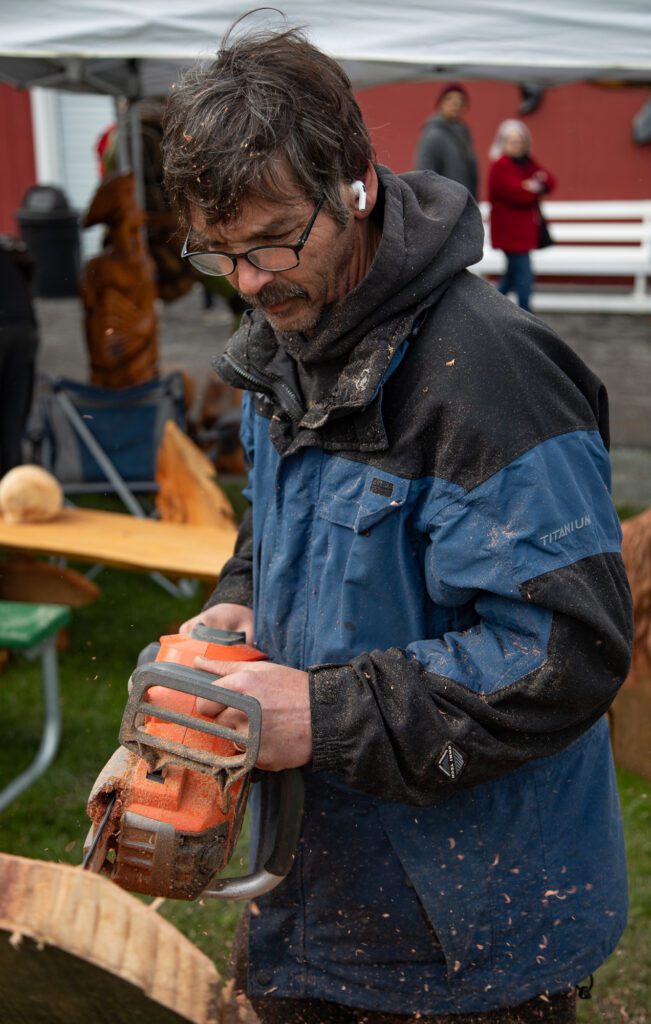Saw dust flies as Joe Littlefield of Anacortes carves into wood with a chainsaw.
