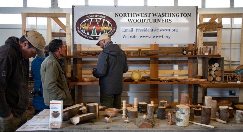 Visitors inspect wood bowls and pieces of logs ready to be turned.