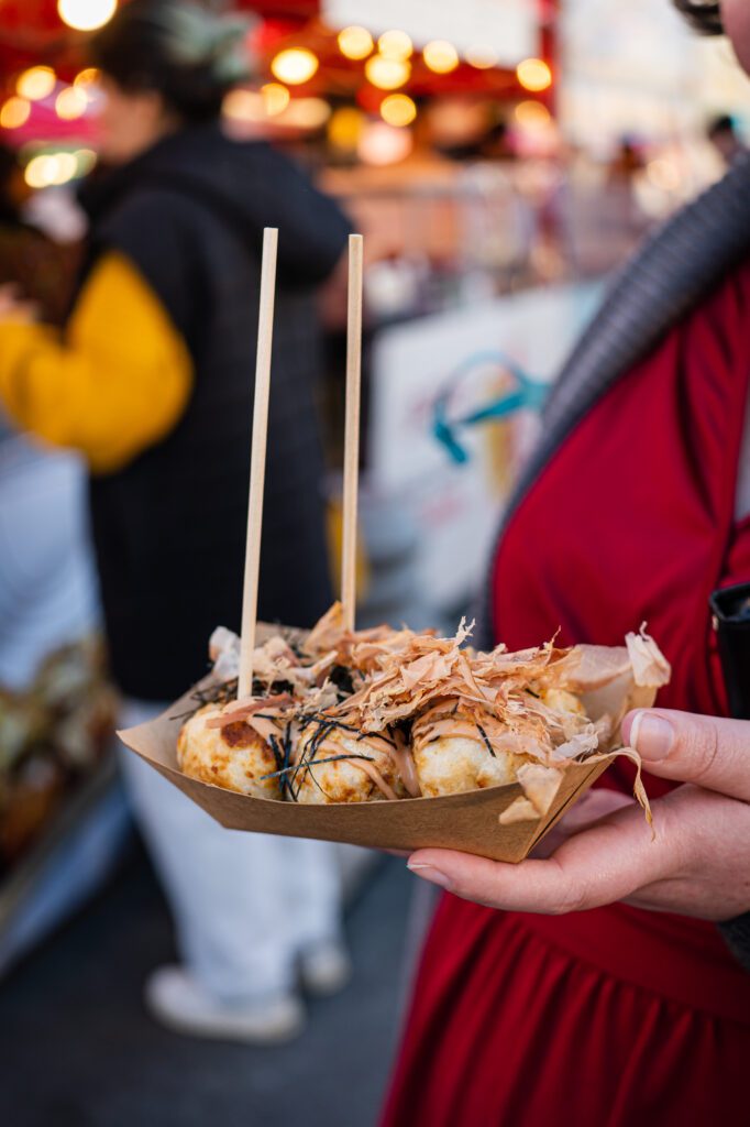 A diner orders classic takoyaki from a stall.