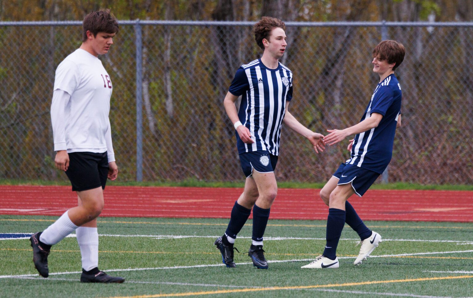 Squalicum's Simon Egner, center, gets a hand from teammate Kellen Savage Thursday, April 11 after scoring a goal as the Storm beat Lakewood 7-1 at Squalicum High School.