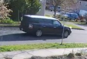 A black and white Ford Flex SUV on a road near trees.
