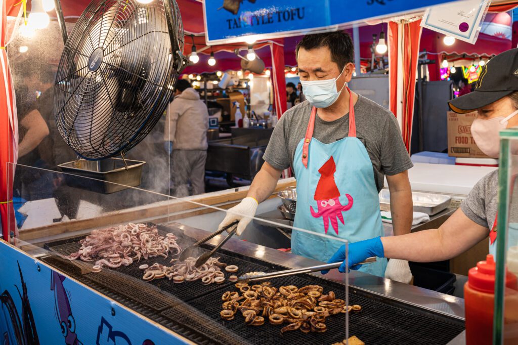 A vendor cooks squid at the Richmond Night Market. Waiting diners can watch vendors prepare and assemble food at almost every stall.