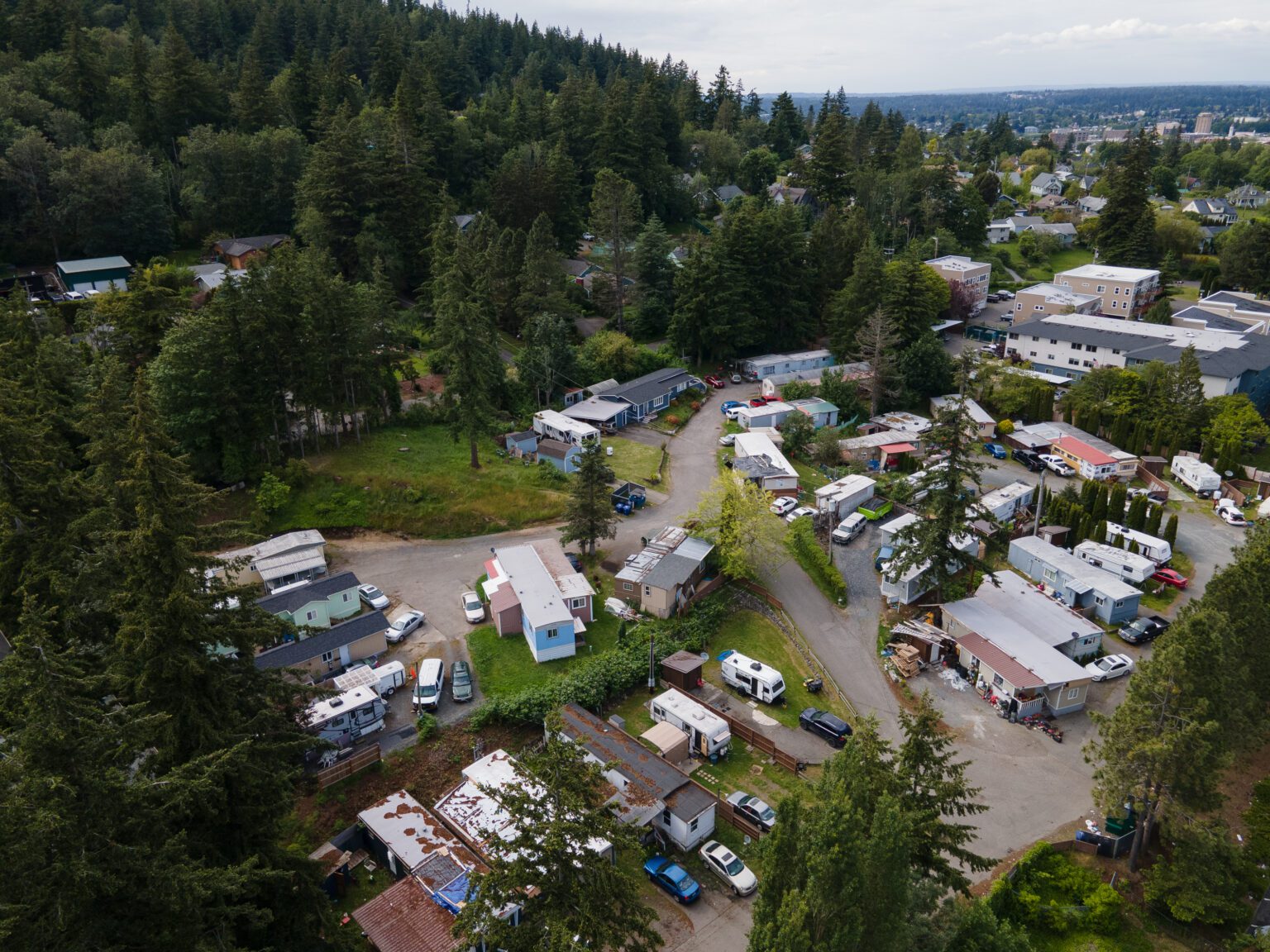 Samish Mobile Home Park with multiple mobile homes, cars and residential buildings surrounded by trees and other larger apartment complexes.