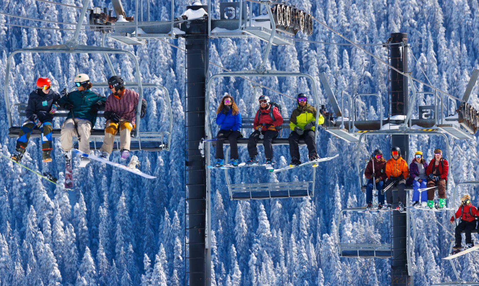 Skiers ride a lift at Mt. Baker Ski Area, all dressed in different colorful winter gear.