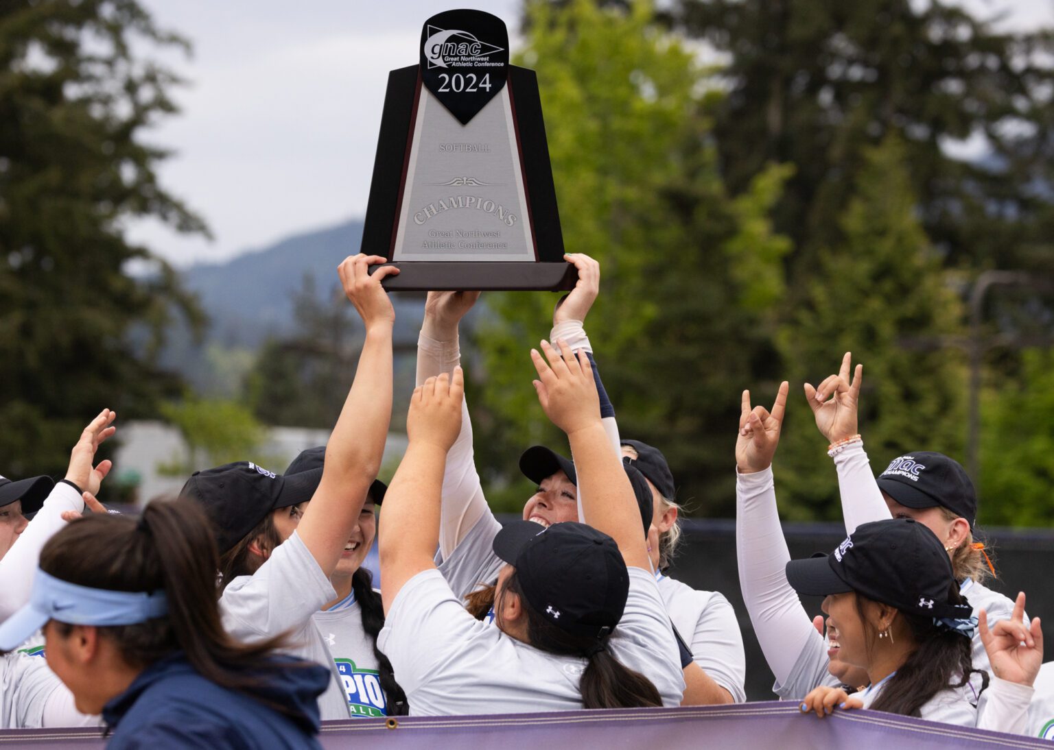 Western seniors Taylor Khorrami, left, and Emily Paulson hoist the Great Northwest Athletic Conference Tournament trophy Saturday, May 4 after beating Northwest Nazarene University 4-0 at Viking Field.
