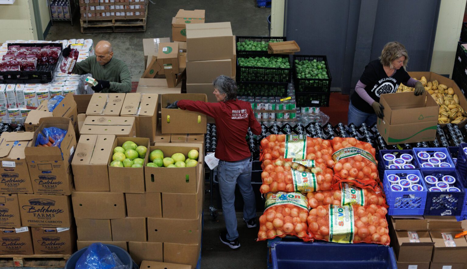 Volunteers Buzz Hagshenas, Arlane Olson and Tamara Godbey sort through boxes of fresh produce and canned food.